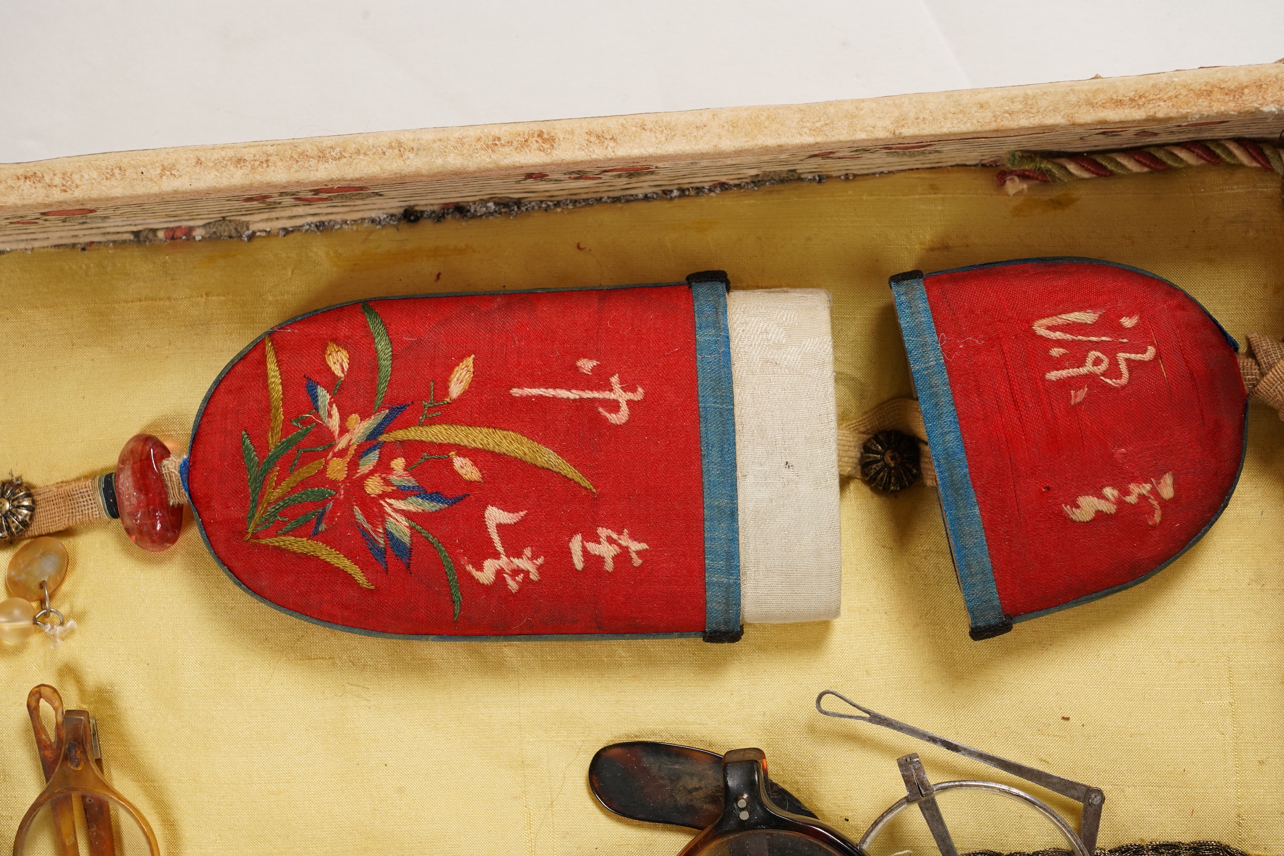 A collection of 19th/20th century Chinese embroidered silk spectacle cases and various spectacles, Box 33cm square